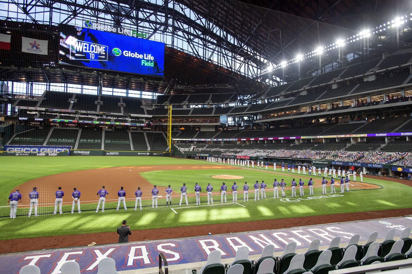 FILE - The Texas Rangers and Colorado Rockies line the foul lines of Globe Life Field before an opening day baseball game in Arlingtn, Texas, in this Friday, July 24, 2020, file photo. The Texas Rangers could have a full house for their home opener next month after debuting their new 40,518-seat stadium without fans in the stands for their games last season. If that happens, the Rangers could be the first team in MLB or any U.S.-based sport to have a full-capacity crowd since the coronavirus pandemic started rapidly shutting down sports a year ago this week. (AP Photo/Jeffrey McWhorter, File)